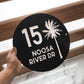A circular coastal house sign that features the house number, street name and a detailed palm tree . Made from UV stable acrylic suitable for external use. 