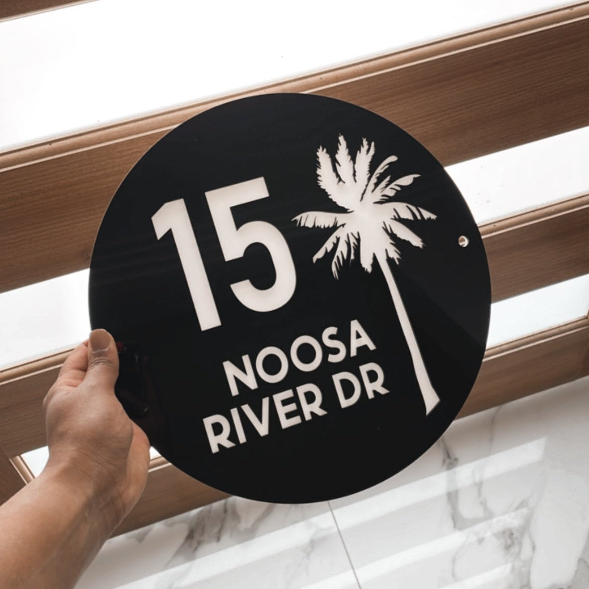 A circular coastal house sign that features the house number, street name and a detailed palm tree . Made from UV stable acrylic suitable for external use. 